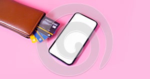 Shopping and payment with smartphone and credit card in brown wallet on pink background.Consumers can buy everything from online s