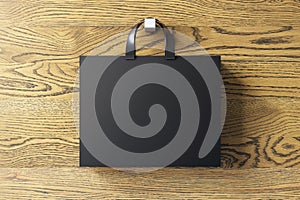 Shopping or present concept with front view on blank black paper bag with silver handles and place for company logo or advertising