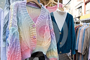 A shopping rank filled with clothes, colorful knitted sweaters. Bunch of clothes of different colors for sale.