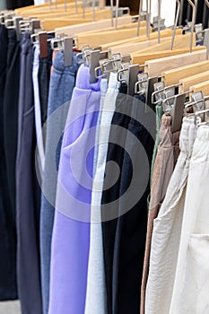 A shopping rank filled with clothes, pants, sports clothes. Bunch of clothes of different colors for sale.