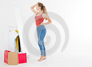 Shopping sale concept. Blonde girl in jeans and t shirt. Young woman in good body shape looking at mirror and lose weight.