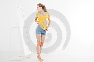 Shopping sale concept. Blonde girl in jeans and t shirt. Young woman in good body shape looking at mirror and lose weight.