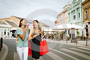 Shopping, sale, happy people and tourism concept. Smiling girls with shopping bags in ctiy