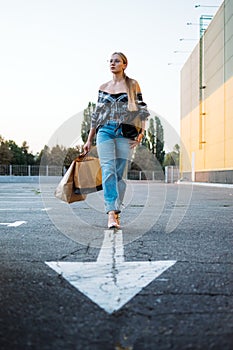 Shopping, sale, Happy young stylish blonde woman with shopping bags go to car in parking on white arrow after shopping