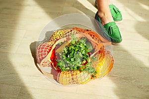 Shopping string grocery reusable mesh bag full of fresh fruits and vegetables on the floor at home