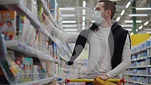 Shopping at supermarket during coronavirus pandemic, man with mask on face