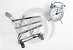 Shopping time. Shopping cart and alarm clock grey color on a white background.