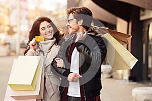 Shopping together. Woman showing credit card to husband