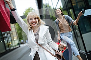 Shopping and tourism concept. Beautiful women with shopping bags in ctiy having fun