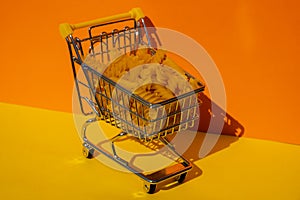 Shopping trolley cart Filled With Pasta on colorful yellow orange isometric background. Copy space for your text. Food