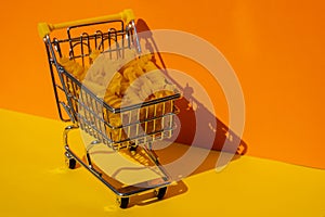 Shopping trolley cart Filled With Pasta on colorful yellow orange isometric background. Copy space for your text. Food