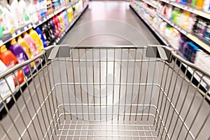 Shopping trolley cart moving in supermarket with motion blur aisle background