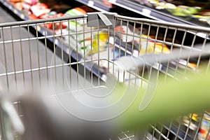 Shopping trolley cart moving in supermarket with motion blur aisle background