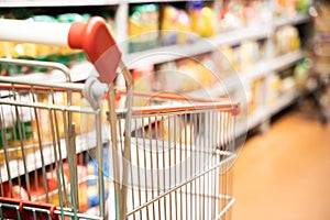 Shopping trolley cart with shallow DOF against supermarket aisle background photo