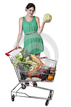 Shopping trolley filled food, young woman is holding a cabbage.