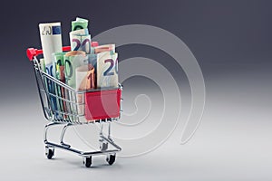 Shopping trolley full of euro money - banknotes - currency. Symbolic example of spending money in shops, or advantageous purchase