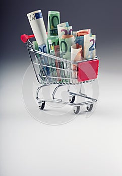 Shopping trolley full of euro money - banknotes - currency. Symbolic example of spending money in shops, or advantageous purchase