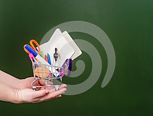 Shopping trolley on the hands near empty green chalkboard