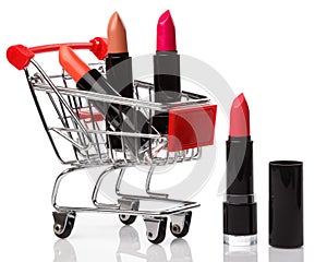 Shopping trolley and lipsticks isolated