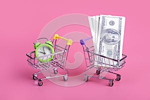 shopping trolley with money and trolley with clock isolated on pastel pink background time is money concept