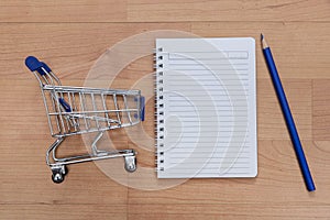 Shopping trolley, notebook and pencil on the table