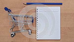 Shopping trolley, notebook and pencil on the table