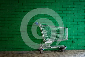 Shopping trolley parked near the shopping center. Brick wall, space for text