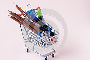 Shopping trolley with stationery items - colored pencils, markers, stapler, clips.