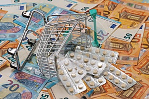 Shopping trolley with tablets on euro bills background, concept of expensive cost of healthcare
