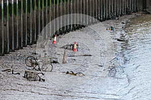 Shopping trolleys, bicycles and other items thrown into a tidal river are being covered over by mud and silt
