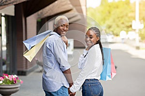 Shopping and walking in city. Smiling african american guy and woman turn around and look at camera