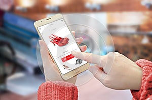 Shopping web site app on smart phone. Woman holding mobile device and buy red shoes