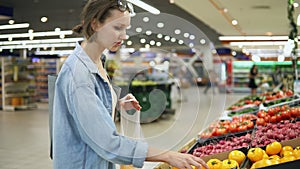 Shopping. Woman choosing bio food yellow tomato in vegetable store or supermarket. Takes one by one and puts it in a