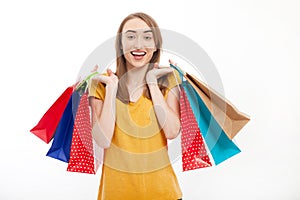 Shopping woman holding colorful bags and smiling on white background with copy space.