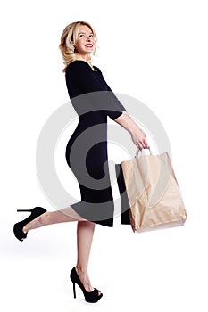 Shopping young woman holding bags isolated on white studio background. Love fashion and sales. Happy blond girl in black luxury gl