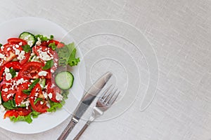 Shopska salad in a white plate on a white tablecloth. The concep