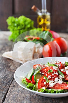 Shopska salad in a white plate on a wooden background, a number