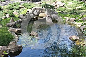 The shore of the artificial pond is lined with large stones.