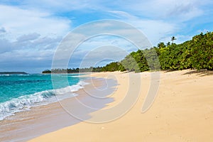 Shore of an azure, turquoise, blue lagoon. Waves, surf, swash at a remote empty idyllic sandy beach on Foa island, Haapai, Tonga.