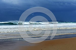 Shore breaking wave with a distant storm