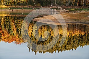 The shore of the lake and trees in autumn colors reflecting on the lake