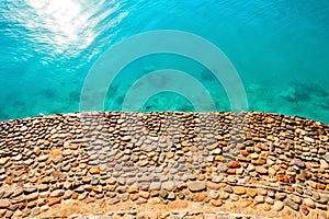 Shore is made of stone with blue clear water