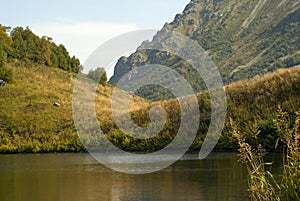 Shore of a mountain lake against the background of a blurry rocky mountain range