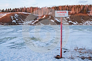 On the shore of the reservoir a sign with the inscription thin ice