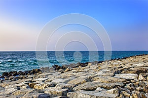 The shore of the sea with large stones - boulders - breakwaters, light waves.