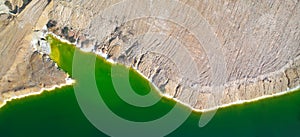 Shore of toxic green lake in abandoned open pit copper mine. Aerial panorama from directly above