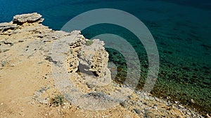 Shoreline arid rock above Sveta Maria beach on Pag Island, Croatia, clear azure blue water.