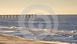 Shoreline at the beach with a pier in the background