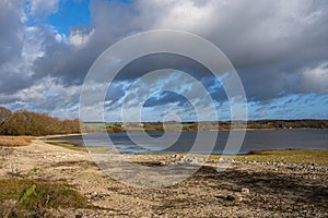A shoreline at a lake with a dramatic sky in the background. Picture from Lake Vomb, Scania, Sweden