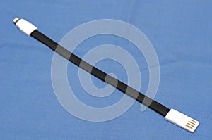 A short black rubber flat data synchronization cable